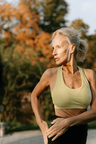 Aging woman exercising outdoors in a park during fall, promoting health, wellness, mobility, and fitness.